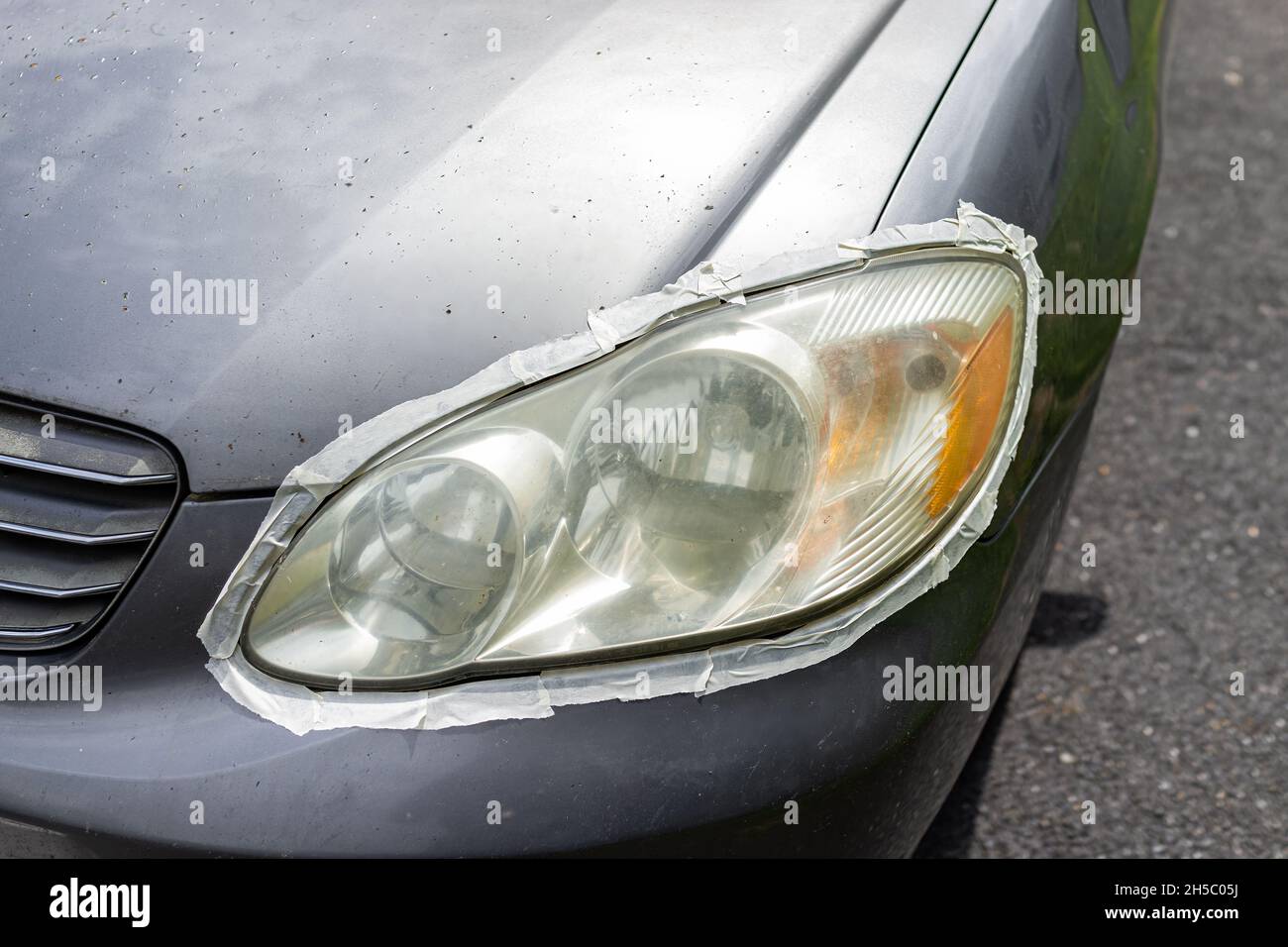 Auto auto auto veicolo anteriore appannamento sporco faro con nastro protettivo intorno alla luce nastrato per proteggere la vernice per la pulizia lucidatura in casa strada di casa Foto Stock