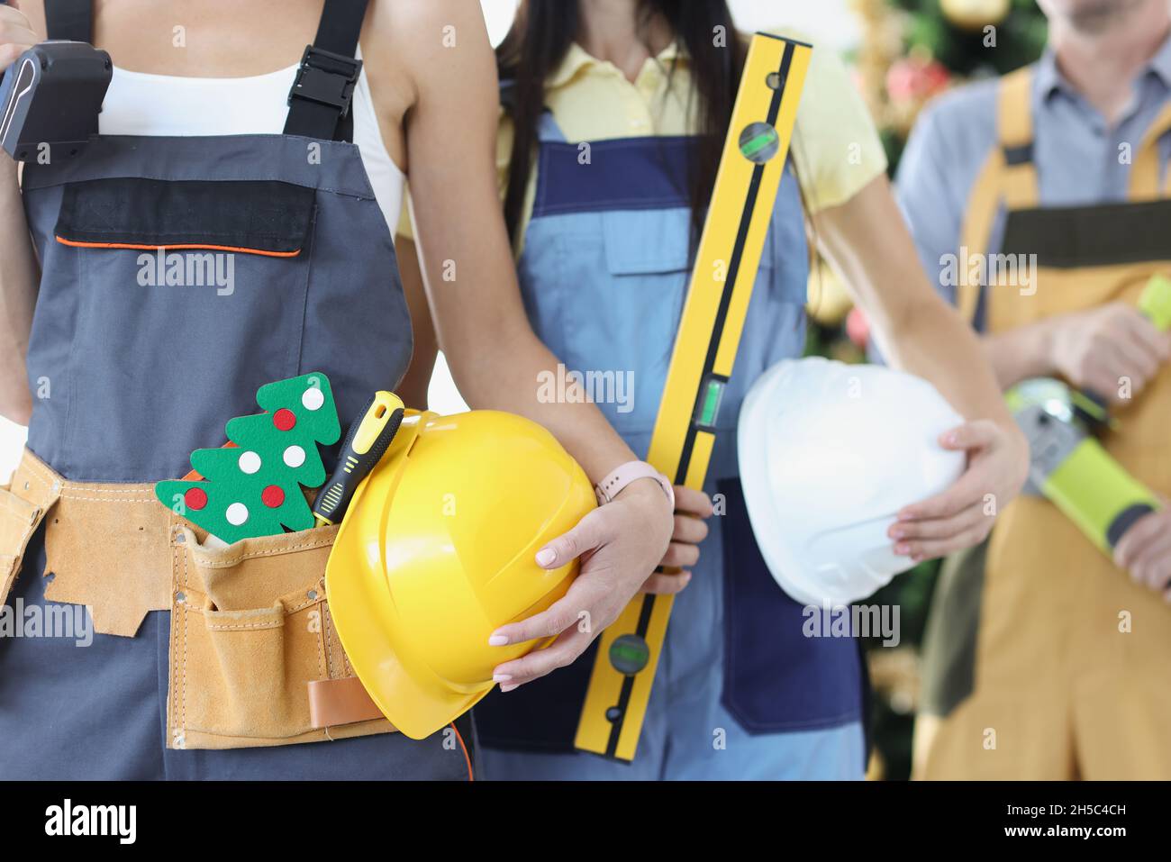 Squadra di costruttori con uno strumento e casco sullo sfondo di albero di Capodanno Foto Stock