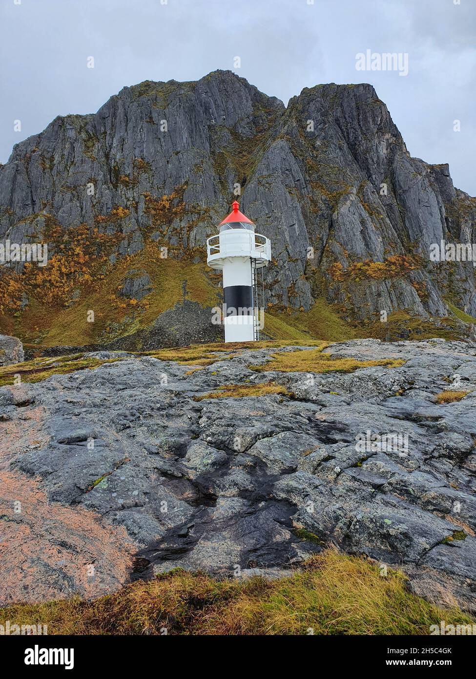 Colpo verticale di un faro sulla collina rocciosa Foto Stock