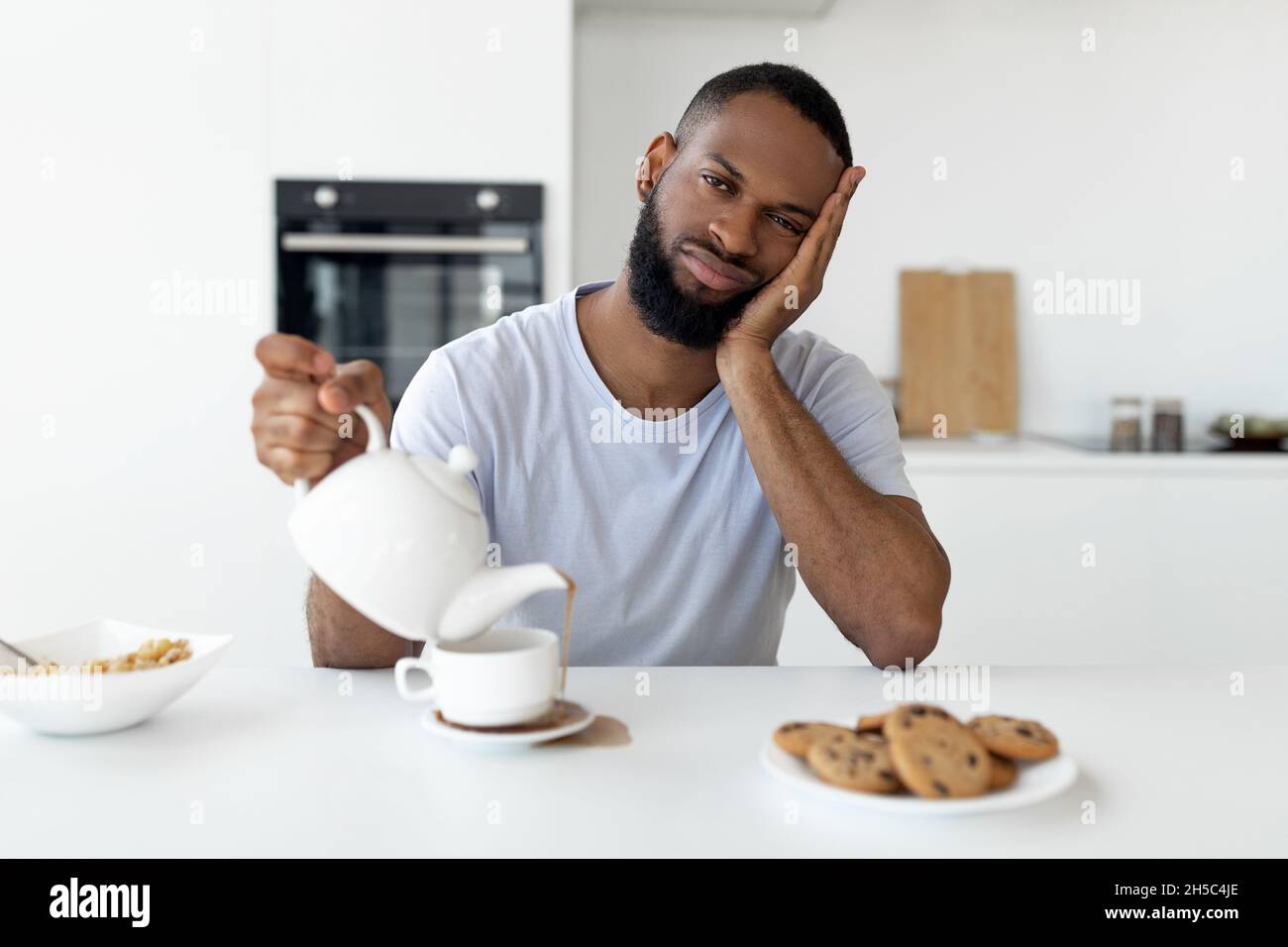 Il ragazzo nero che versa il caffè via dalla tazza che versa la bevanda calda Foto Stock