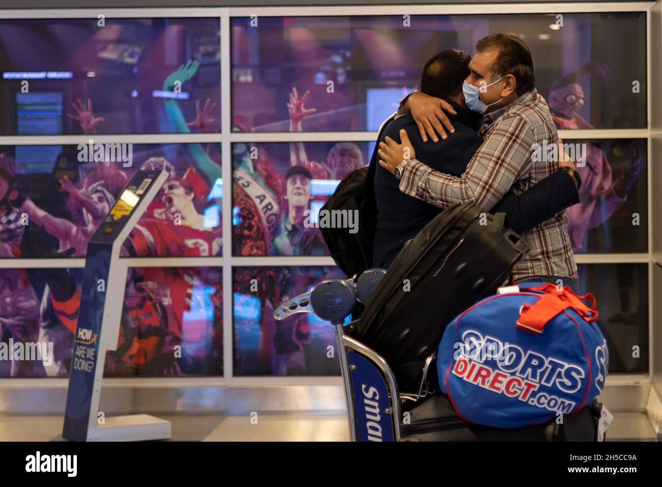 Tehram Qureshi abbraccia un membro della famiglia mentre arriva da Londra all'Aeroporto Internazionale John F. Kennedy a seguito della revoca delle restrizioni all'ingresso di cittadini non statunitensi imposti per contribuire a frenare la diffusione della malattia del coronavirus (COVID-19), a New York, Stati Uniti, 8 novembre 2021. REUTERS/Carlos Barria Foto Stock