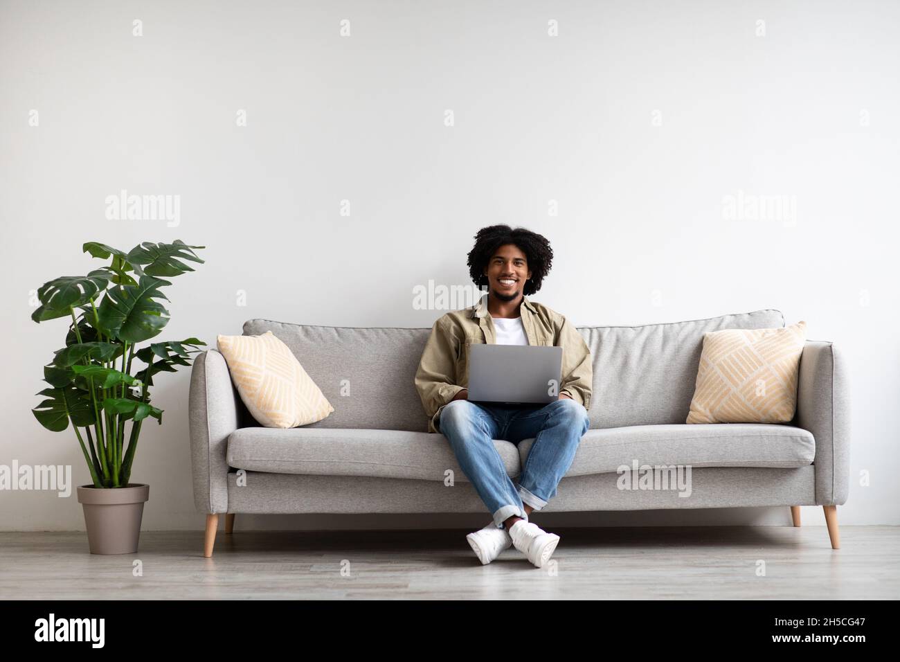 Ritratto di bel sorriso uomo Nero relax sul divano con laptop Foto Stock
