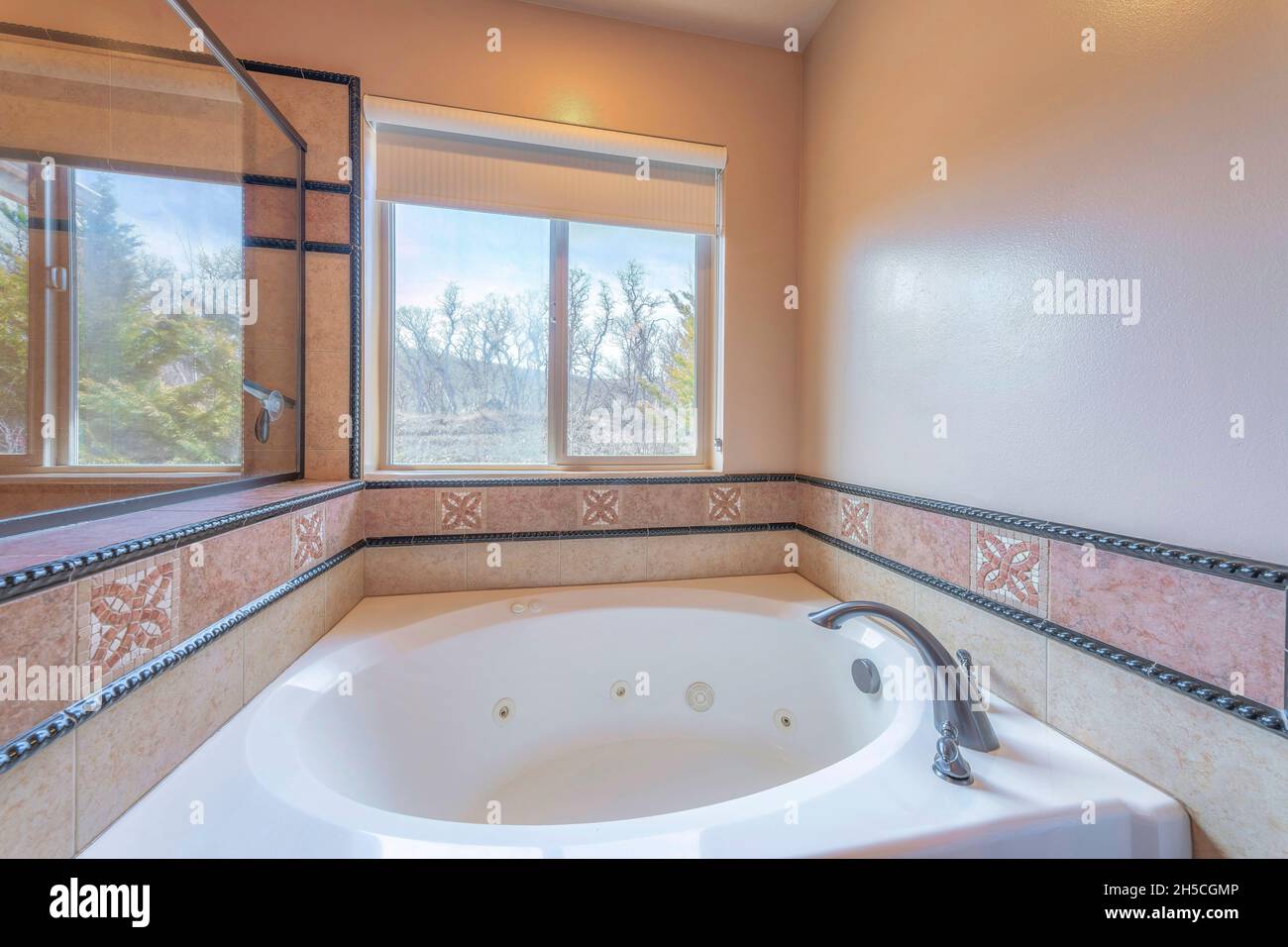 Vasca da bagno con rivestimento decorativo in piastrelle e finiture nere Foto Stock
