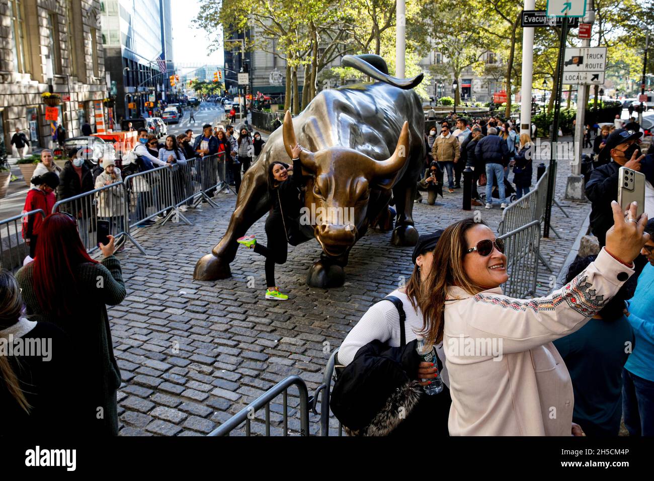 I turisti si riuniscono intorno alla statua di Charging Bull, anche conosciuta come Wall St. Bull, a seguito della revoca delle restrizioni all'ingresso di cittadini non statunitensi imposti per contribuire a contenere la diffusione della malattia di coronavirus (COVID-19), a New York, Stati Uniti, 8 novembre 2021. REUTERS/Brendan McDermid Foto Stock