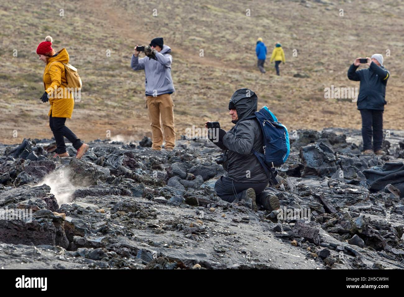 Turisti su roccia lavica di recente eruzione , Islanda, Penisola di Reykjanes, Fagradersfjall Foto Stock