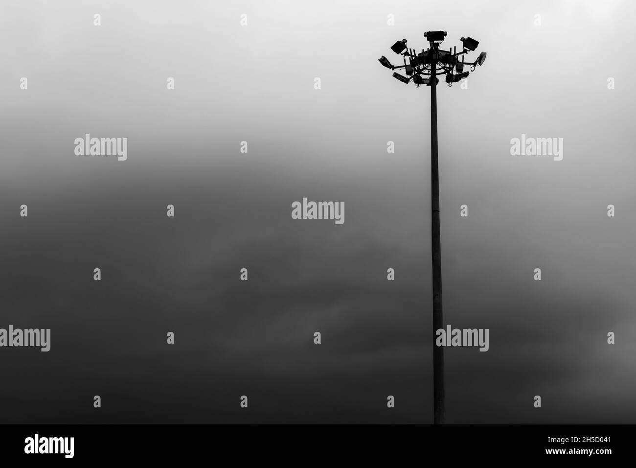 Scatto in scala di grigi di un'alta asta di illuminazione contro un cielo nuvoloso Foto Stock