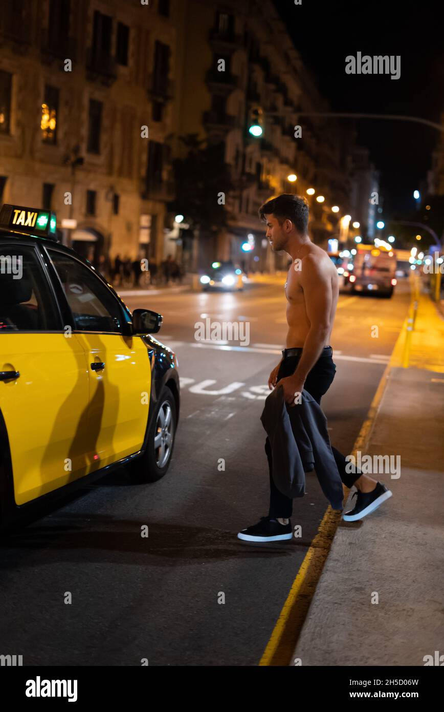 Vista laterale di un uomo adulto che cammina verso il taxi sulla strada della città di notte Foto Stock