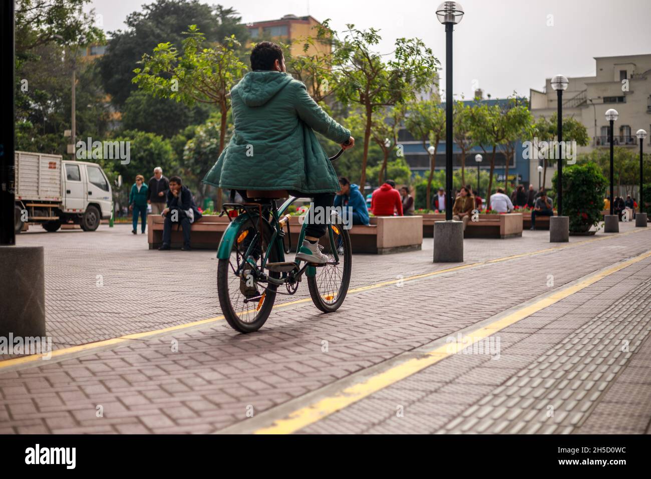 Lima, Perù - 12.02.2019: Persona peruviana che indossa un jaket verde in bicicletta su una pista ciclabile Foto Stock