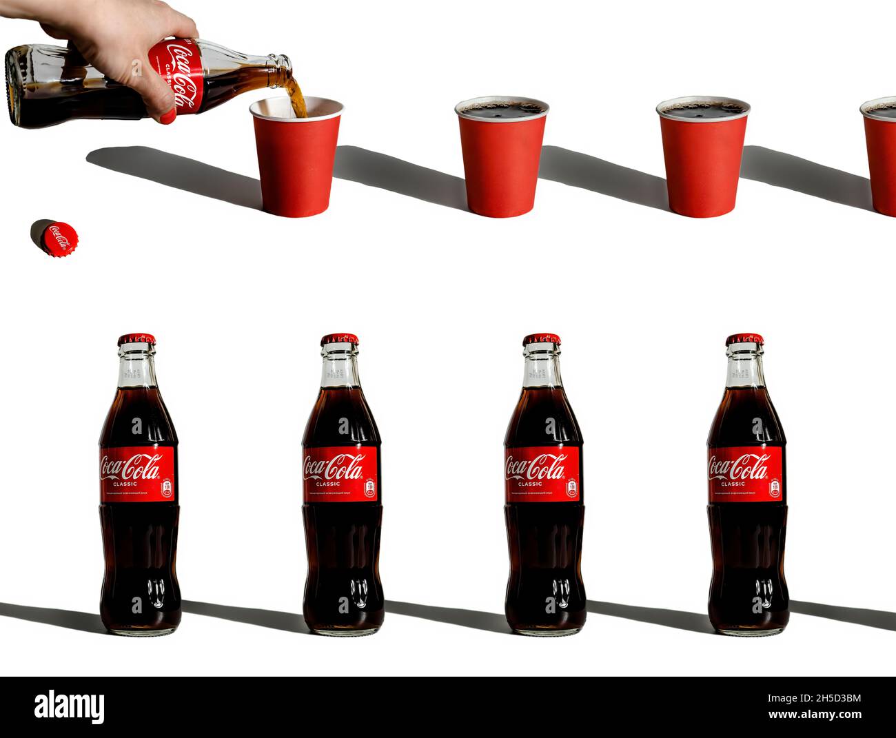 Composizione creativa con bottiglie ripetute di coca-cola e bicchieri di carta Foto Stock