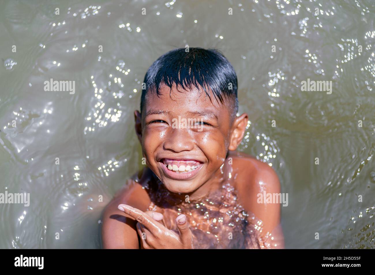 Il ragazzo al molo di Muara Kali sorride felicemente quando sarà fotografato Foto Stock