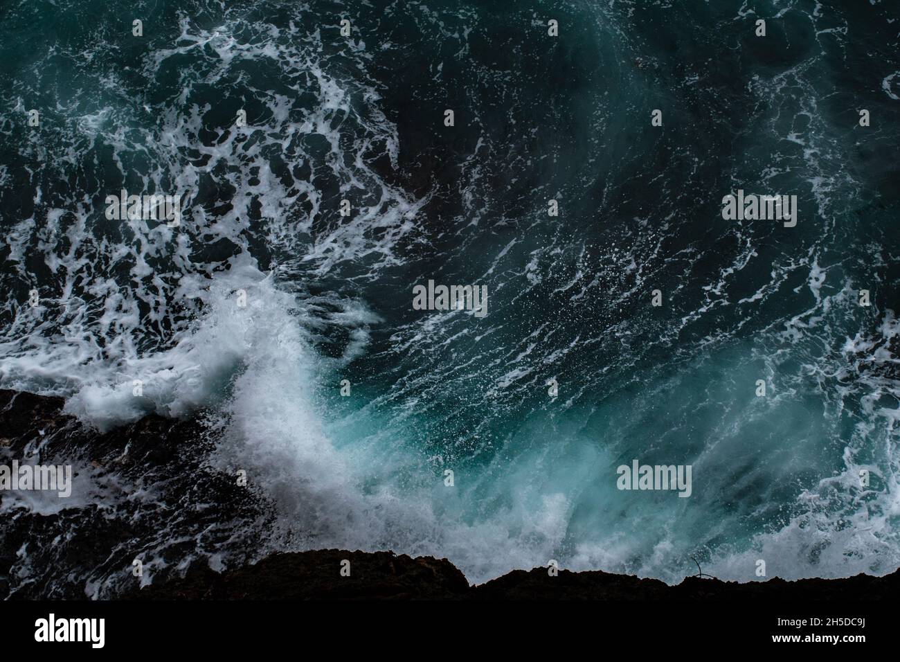 Una potente onda blu forma la spirale d'oro mentre si schianta nelle rocce del Costa Rica. Foto Stock