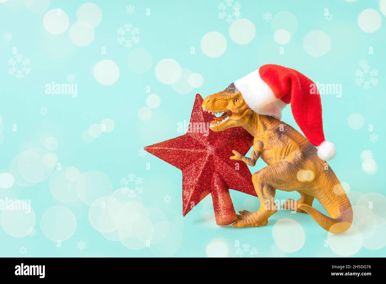 Il Rex del dinosauro in cappello rosso di Babbo Natale tiene la stella nelle relative zampe su sfondo blu la vigilia di Capodanno o la vigilia di Natale scheda di festa di arte creativa idea per Merry Foto Stock