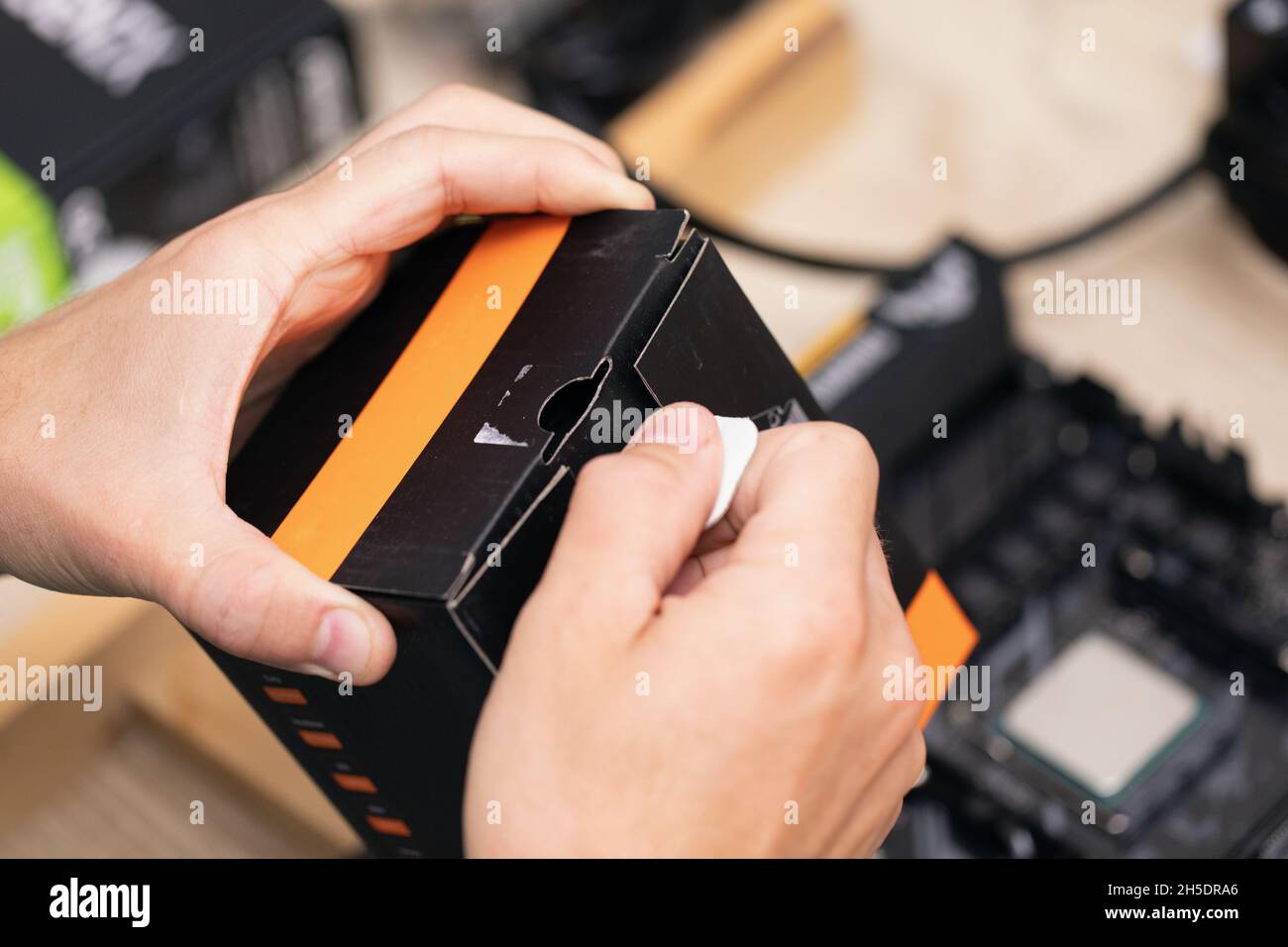 man opening scatola nera e arancione costituita da alcuni componenti elettronici su tavola in legno. Computer guasto. Programmatore futuro. Foto Stock