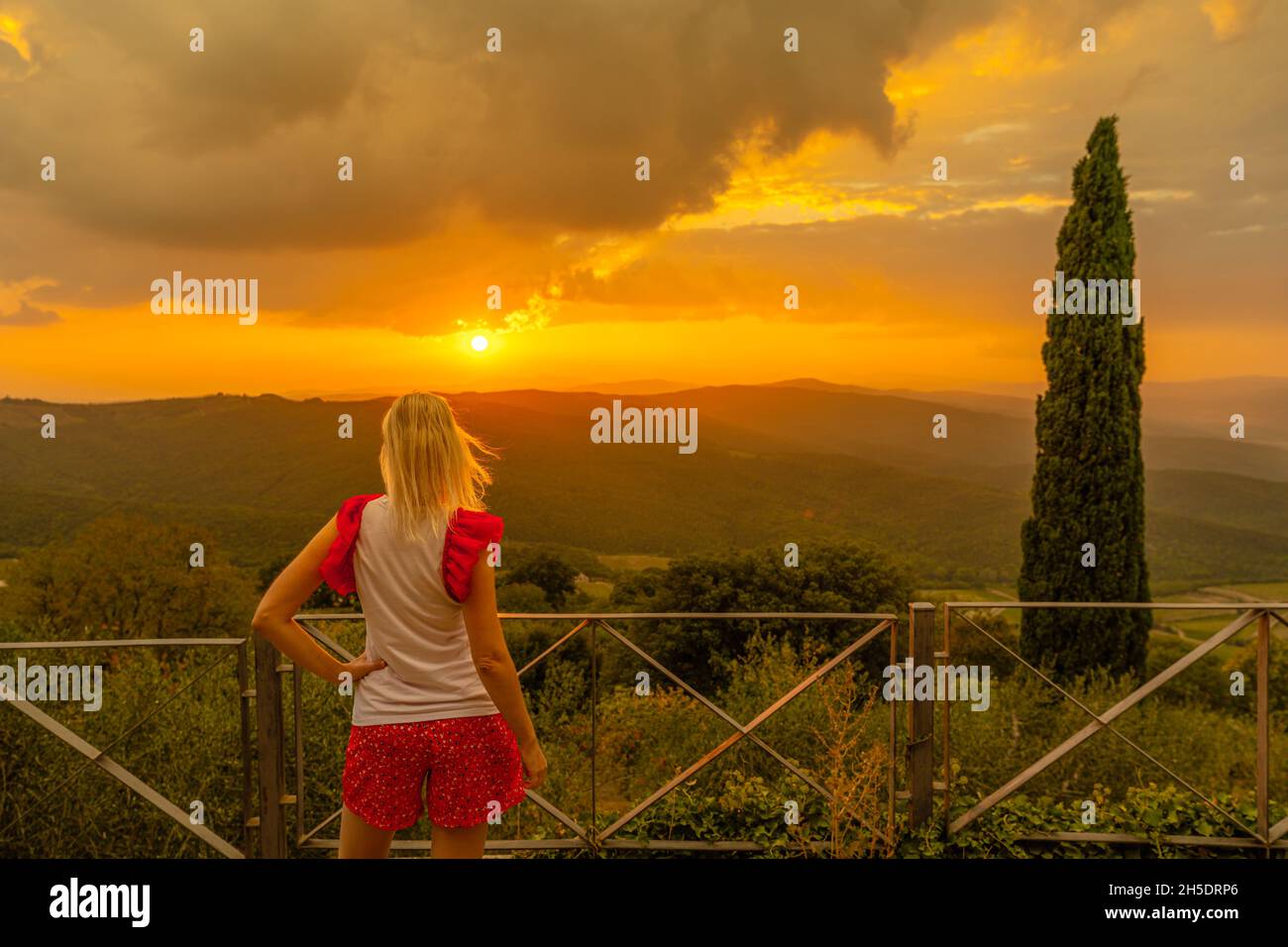 Donna che guarda il tramonto nei vigneti terrazzati del borgo enogratore toscano in Toscana nella campagna italiana. Patrimonio vigneti d'Italia Foto Stock