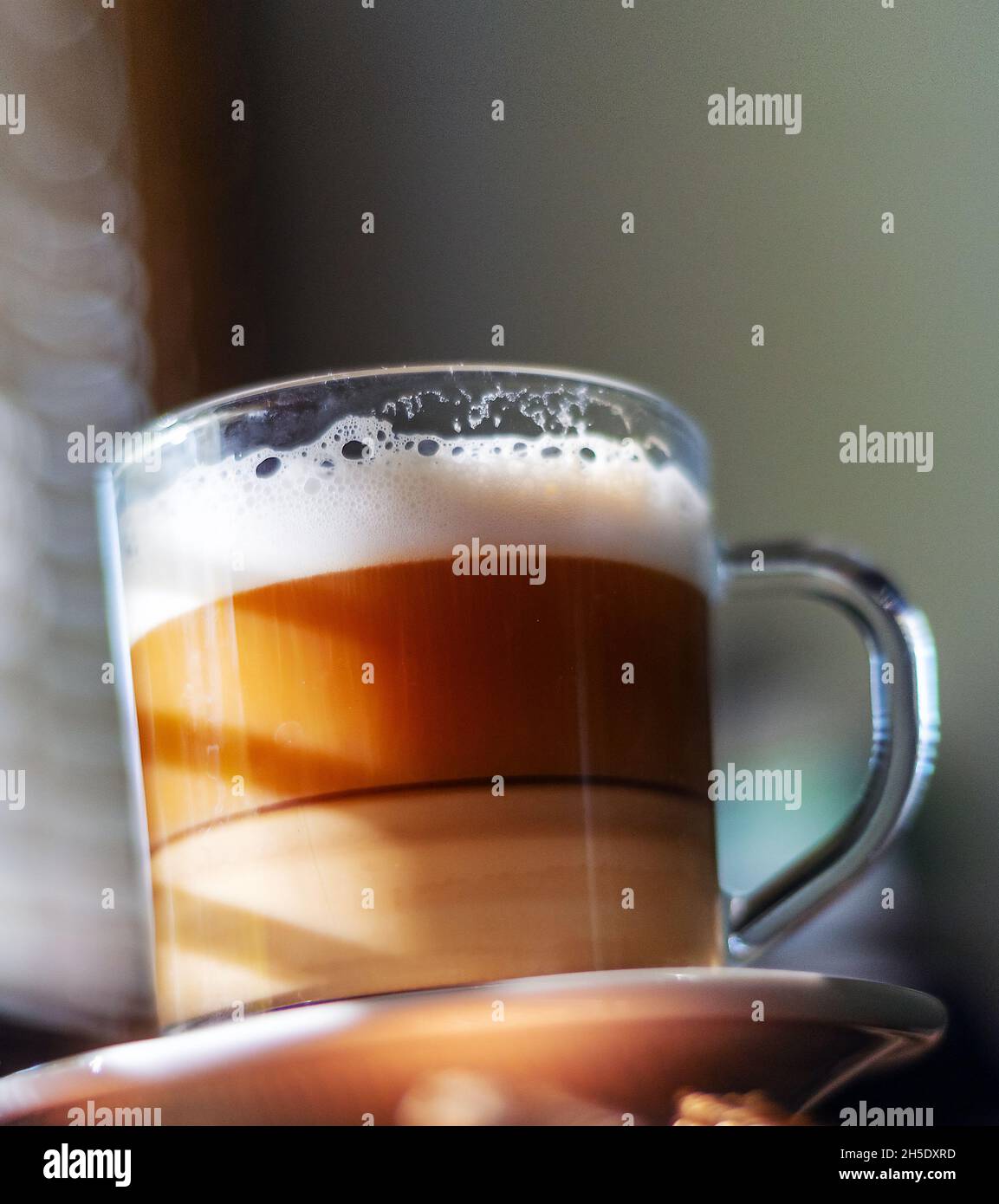 Tazza di vetro del mattino con latte su sfondo sfocato primo piano punto di vista. Foto Stock