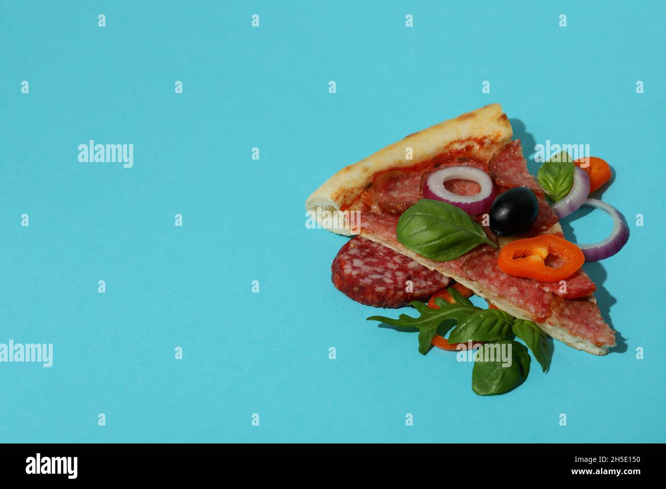 Fetta di pizza al salame su sfondo blu Foto Stock