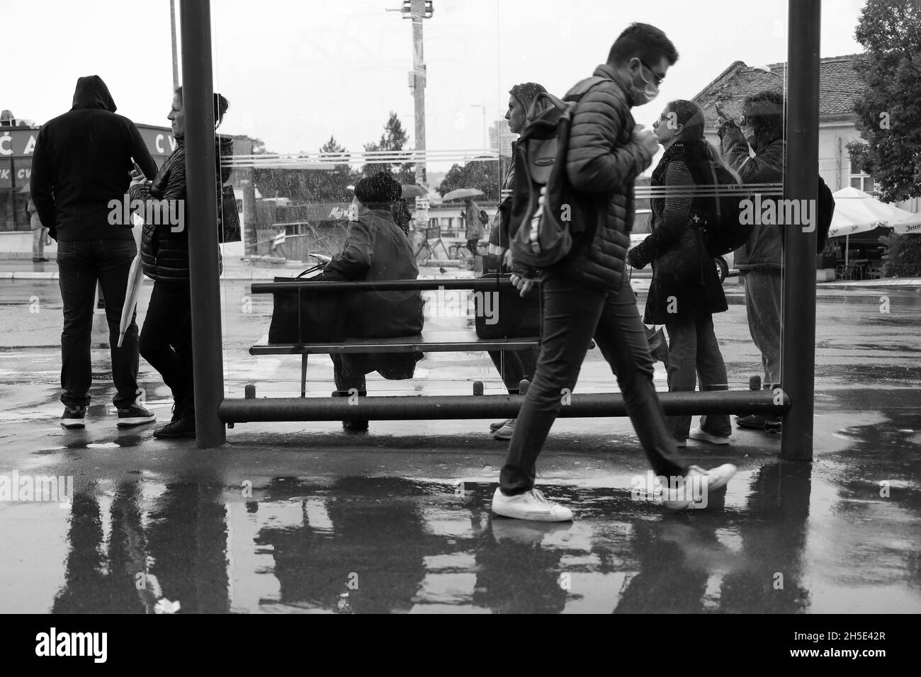 Belgrado, Serbia, 7 ottobre 2021: Passeggeri in attesa di un autobus urbano sotto la pioggia (B/N) Foto Stock