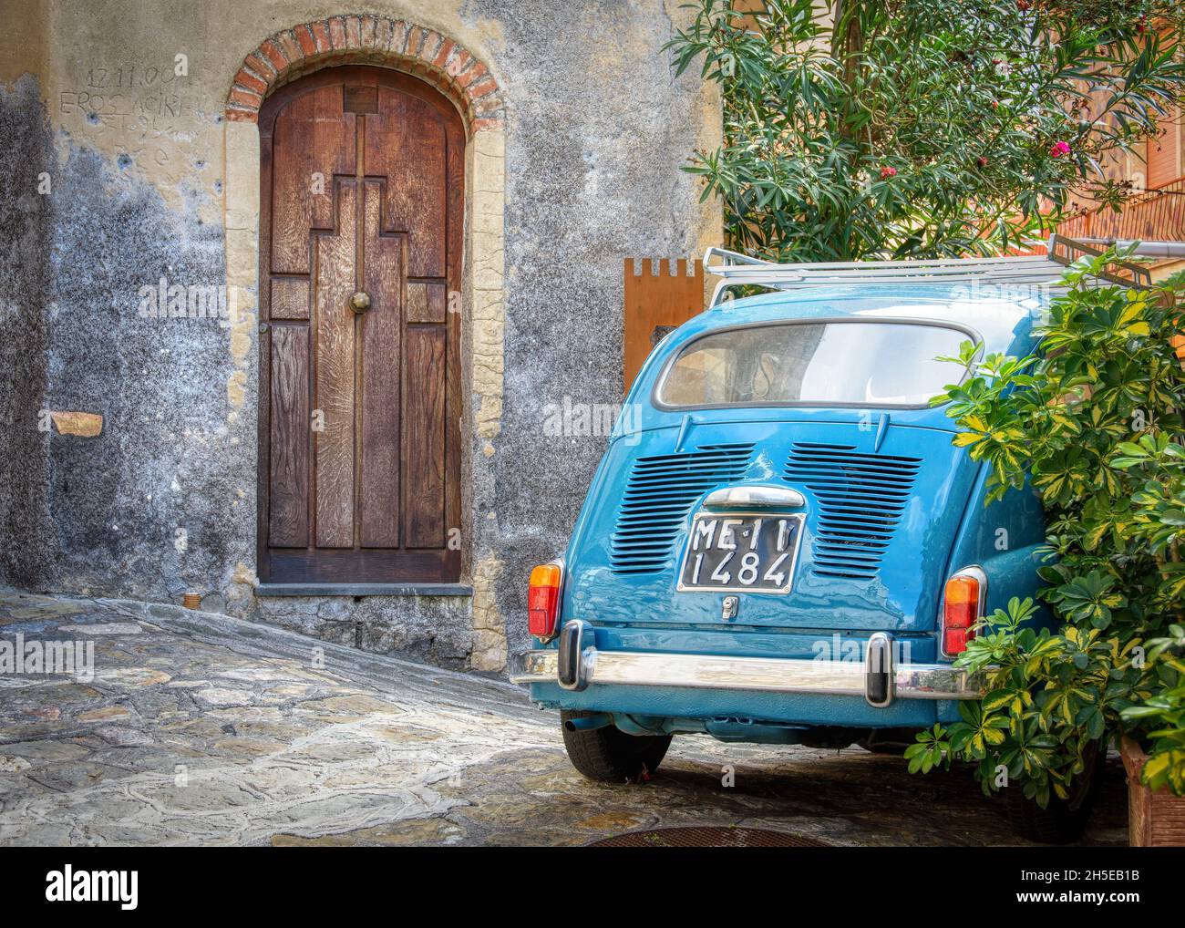 Sicilia, Italia - 14 ottobre 2015 : una Fiat 600 è parcheggiata accanto ad un vecchio edificio con una interessante porta in legno. Foto Stock