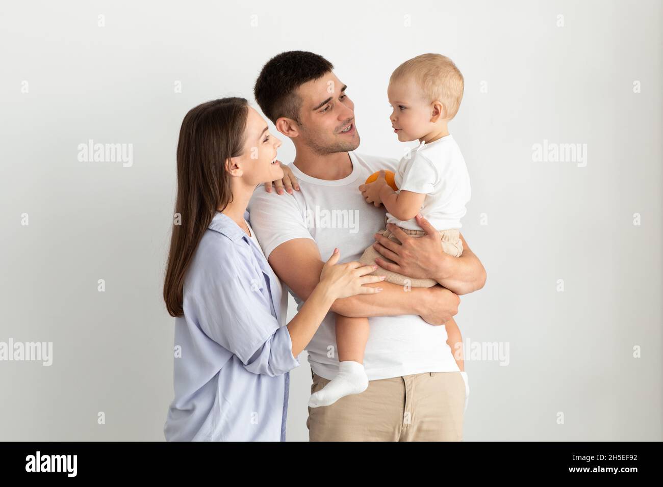 Concetto di genitorialità. Ritratto dei giovani genitori felici che tiene il loro bambino infantile carino Foto Stock