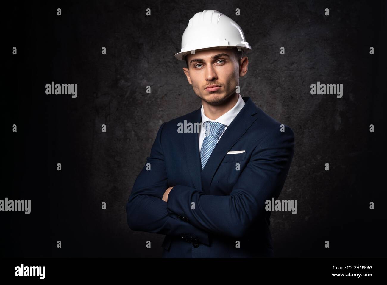 Giovane architetto caucasico, con casco di sicurezza bianco per la costruzione. Primo piano, con un volto intelligente. Foto Stock
