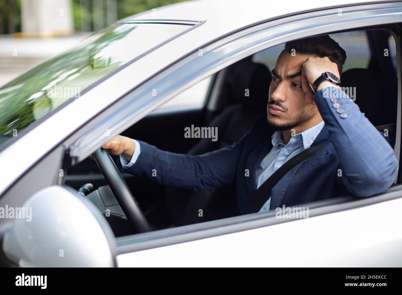 Uomo stressante che va all'aeroporto in auto, bloccato nel traffico Foto Stock