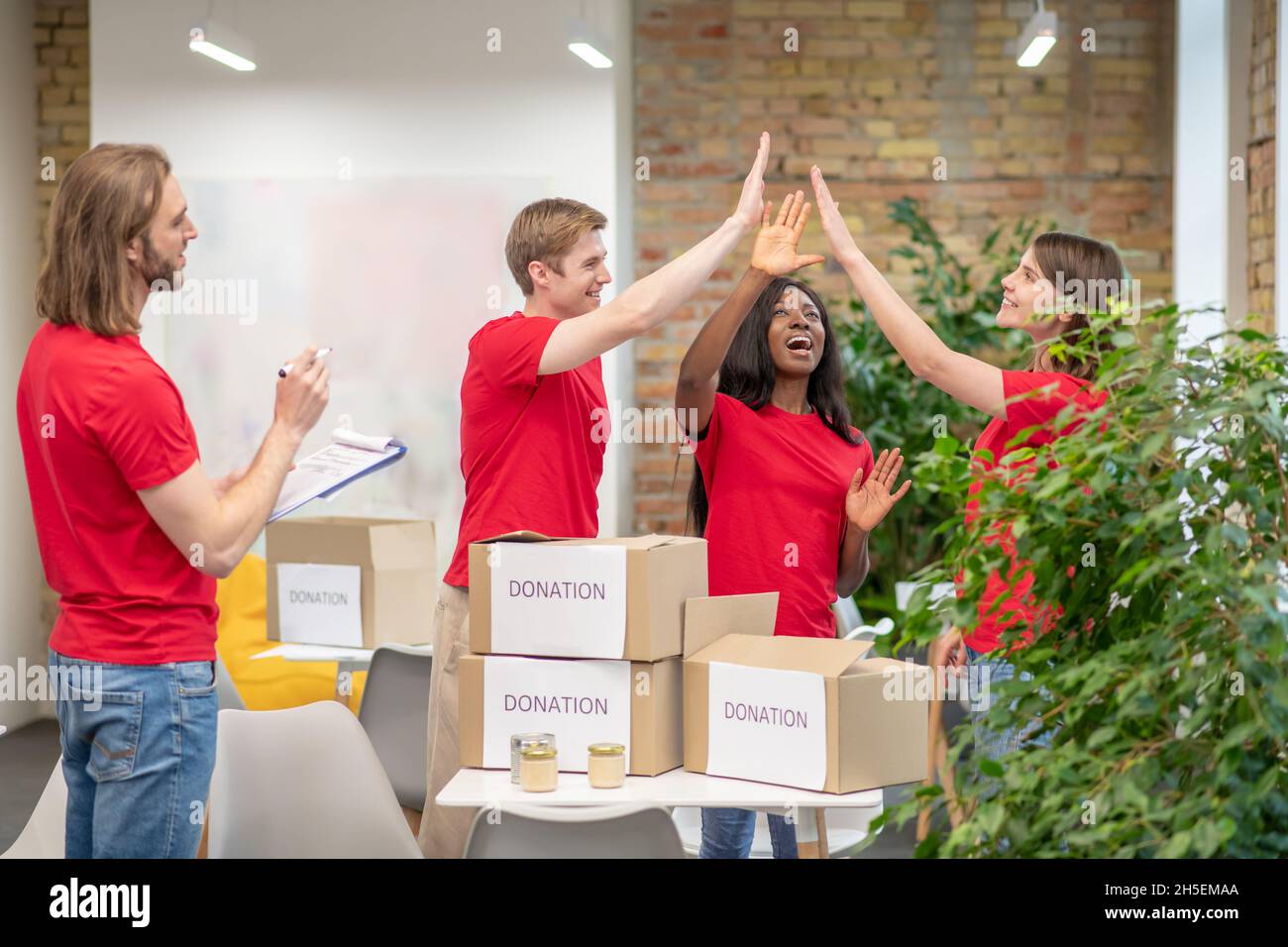 Giovani volontari in magliette rosse al lavoro in un punto di distribuzione Foto Stock