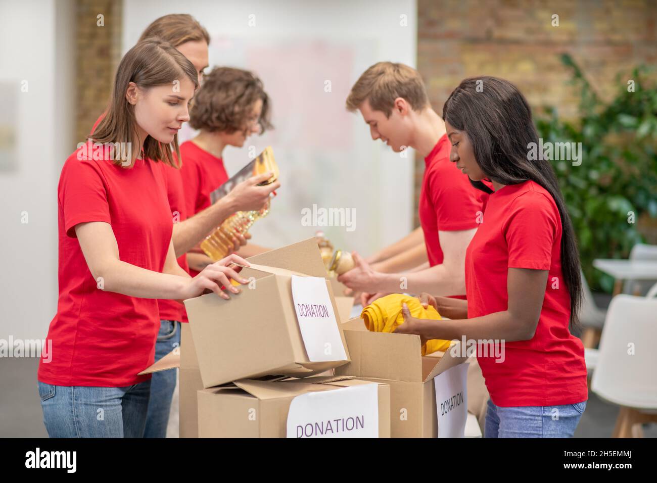 Giovani che lavorano in un centro di distribuzione delle donazioni Foto Stock