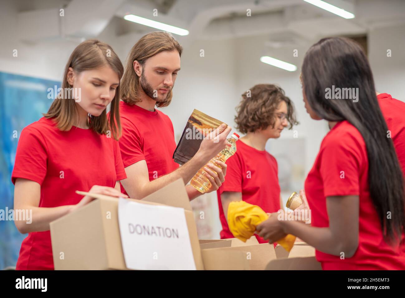 Giovani che lavorano in un centro di distribuzione delle donazioni Foto Stock