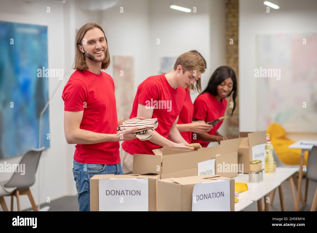 Giovane Peeple in rosso imballando le schede con aiuto umanitario Foto Stock
