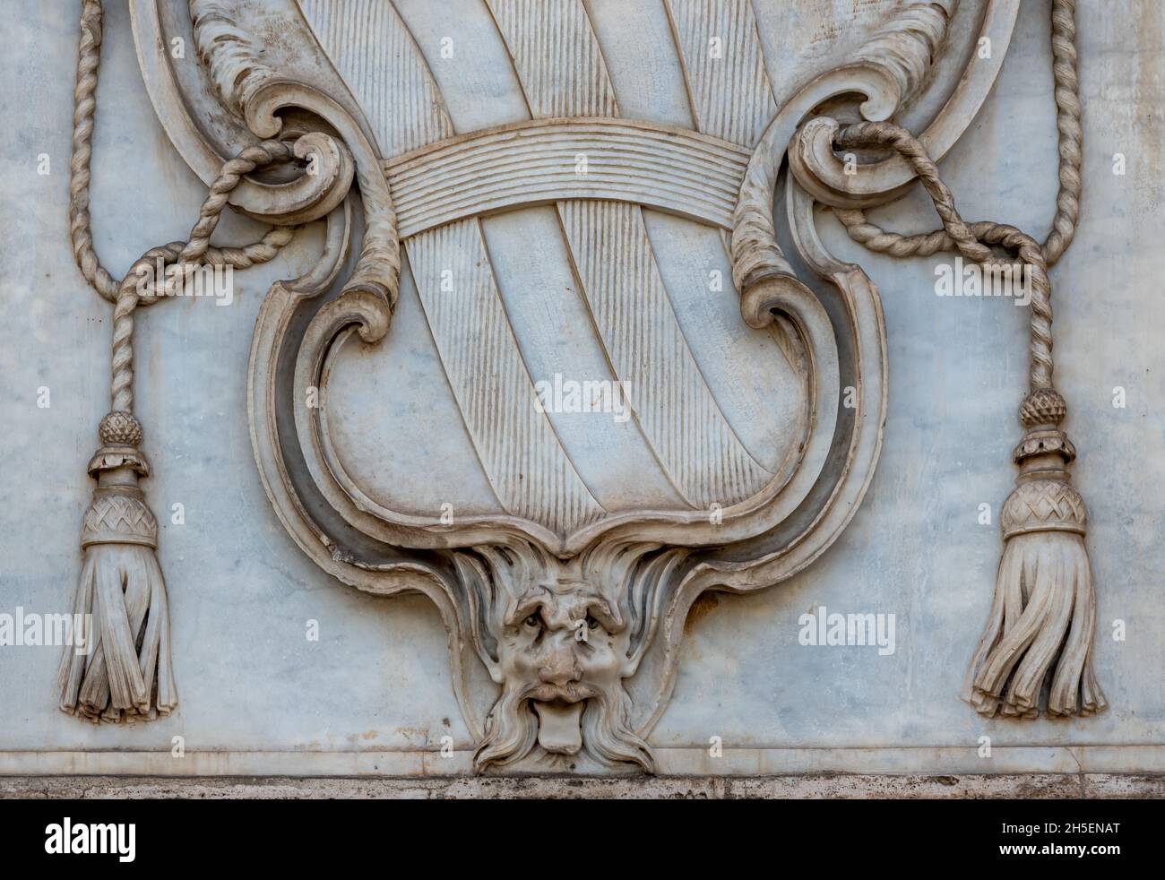 Primo piano sullo stemma del Vaticano scolpito su una parete di marmo che mostra nella parte inferiore un volto monstruo che attacca la lingua Foto Stock