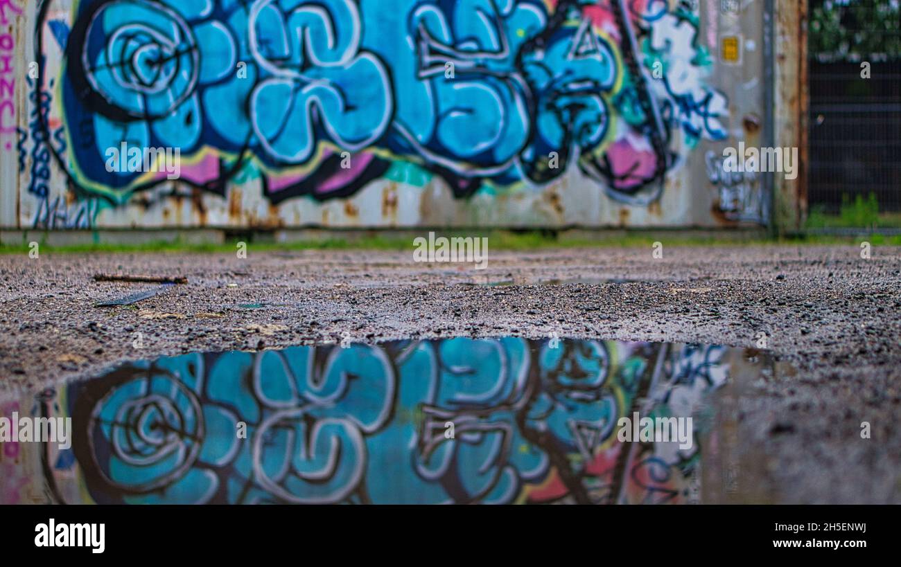 graffiti su un muro riflesso in una pozza. Vista da terra Foto Stock