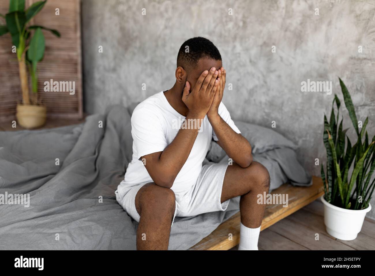 Uomo nero che soffre di mal di testa o di emicrania a letto Foto Stock
