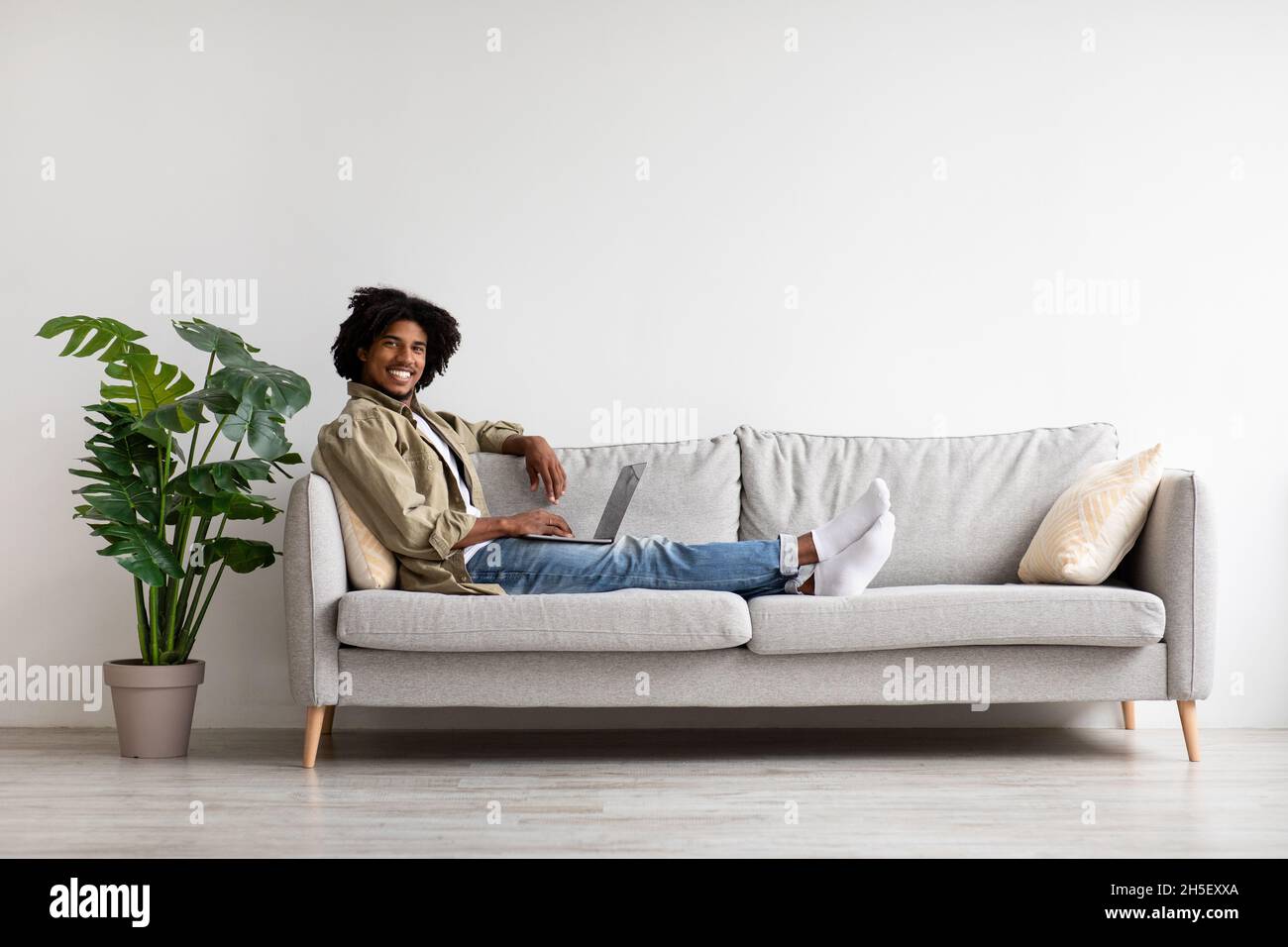 Carriera freelance. Uomo nero rilassato che lavora con il laptop mentre si siede sul divano Foto Stock