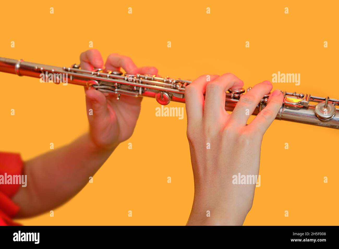 Mani di una musicista donna con un flauto su uno sfondo giallo studio. Flauto con un grande concerto di flauto trasversale, primo piano Foto Stock