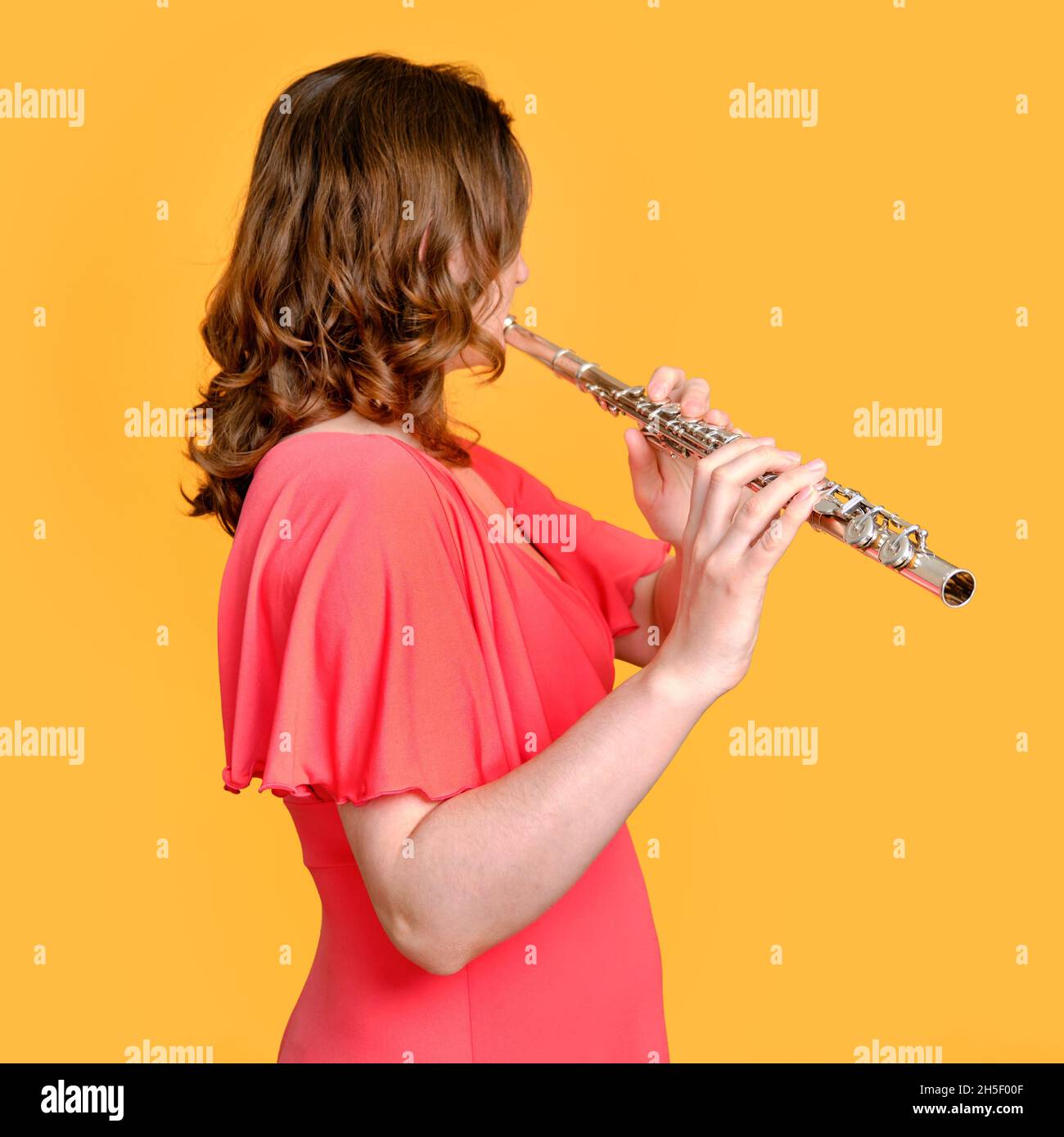 Donna musicista con un flauto su sfondo giallo studio. Flauto con un grande concerto di flauto trasversale, primo piano Foto Stock