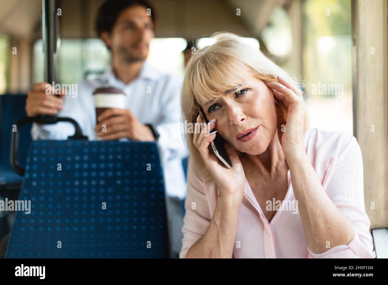 Signora matura che parla al telefono che si collega l'orecchio con il dito Foto Stock