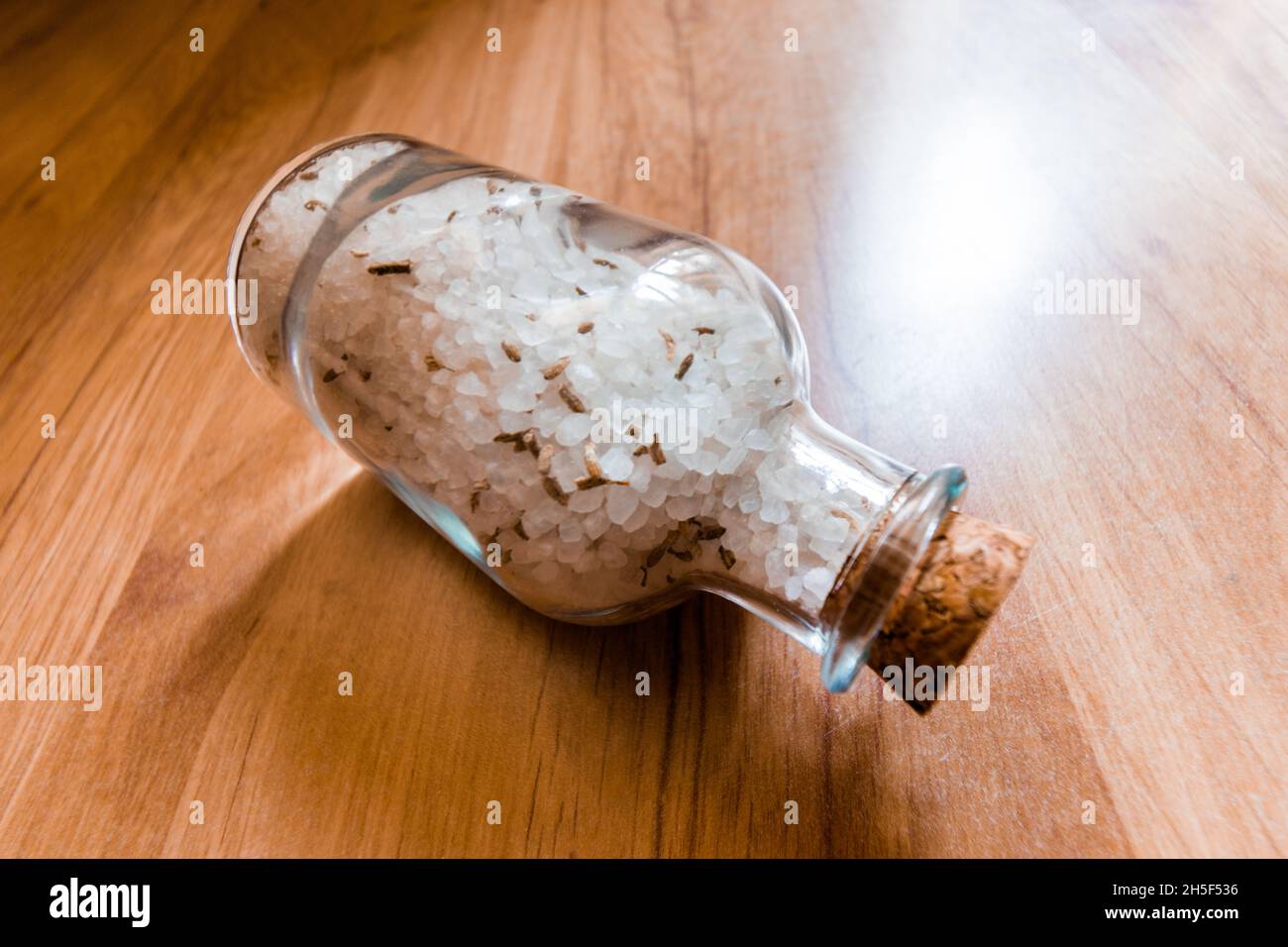 Sale marino bianco con lavanda in una ciotola di vetro su sfondo di legno. Foto Stock