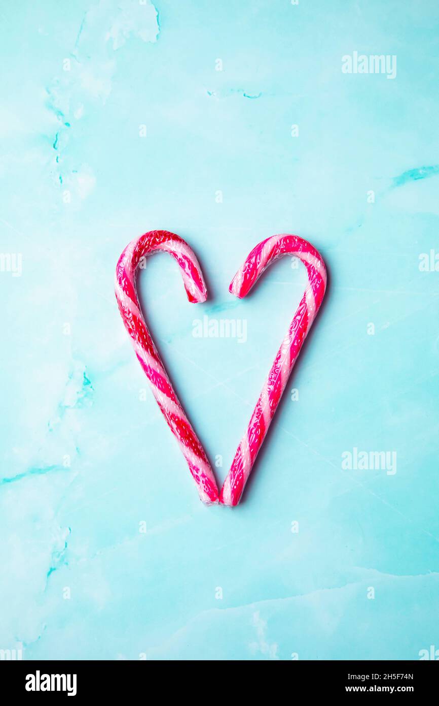 Caramella canna facendo un cuore su uno sfondo azzurro chiaro, Candy canna cuore Natale sfondo vista dall'alto con spazio copia. Buon Natale,Natale,vacanza Foto Stock