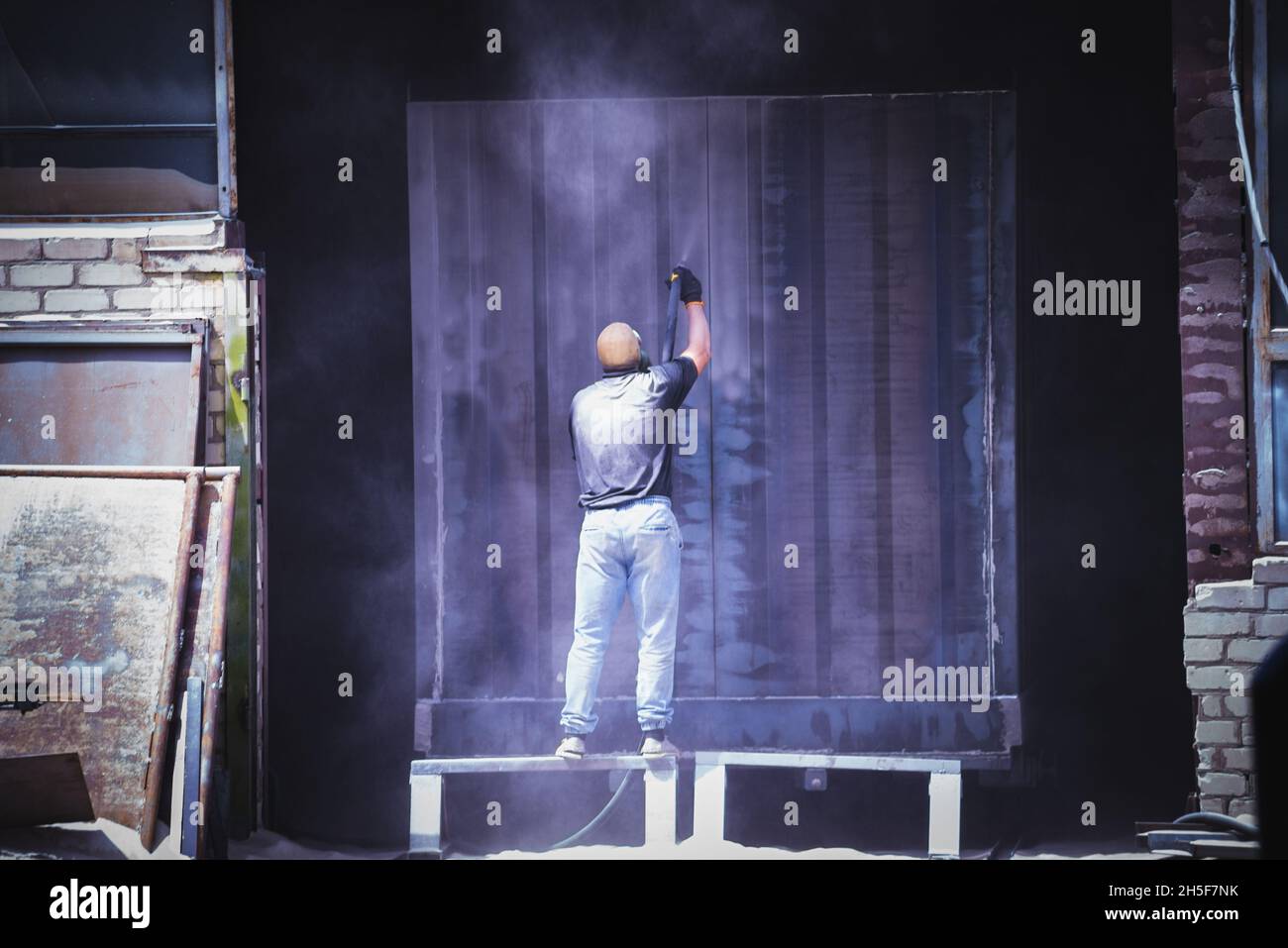 Un uomo insabbia il metallo ad alta pressione Foto Stock