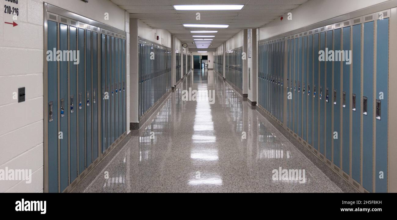 Corridoio americano della scuola superiore fiancheggiato con armadietti e luci riflettin sul pavimento Foto Stock