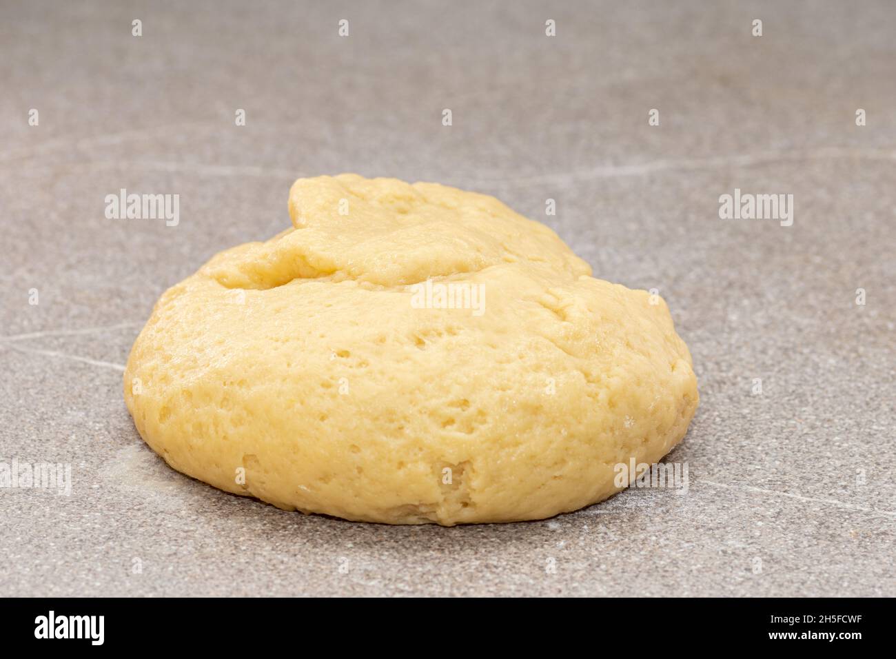 Pasta fresca gialla cruda a forma di palla per la cottura degli uomini di pan di zenzero per Natale su sfondo grigio. Il processo di creazione dei cookie a casa. CH Foto Stock