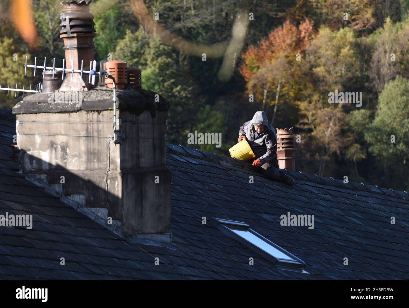 Costruttore uomo riparazione tetto in casa senza attrezzature per la salute e la sicurezza Gran Bretagna, Regno Unito Foto Stock