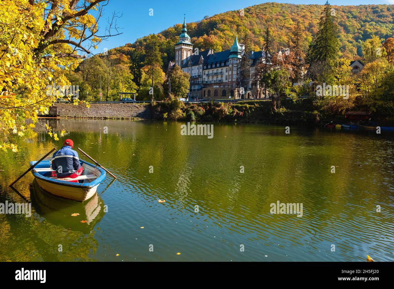 Un uomo seduto in una barca a pedalò di fronte al Palace Hotel in autunno , Lillafüred, Ungheria Foto Stock
