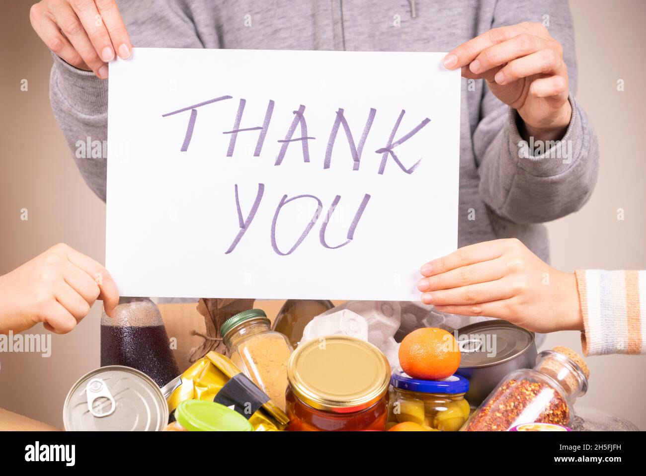Grazie per la donazione. Volontari in possesso di foglio di carta con messaggio grazie sopra la scatola di donazione di cibo piena di drogheria Foto Stock