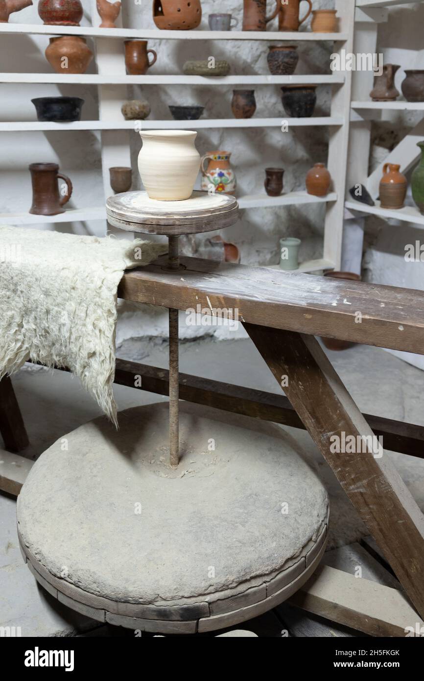 Studio laboratorio di ceramica, vaso di argilla bianca si trova su una ruota di ceramica, foto verticale Foto Stock