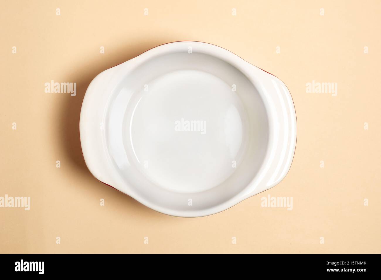 Vista dall'alto del recipiente vuoto per zuppa in ceramica isolato su sfondo beige. Recipiente vuoto in ceramica. Posa piatta di utensili per la cottura Foto Stock