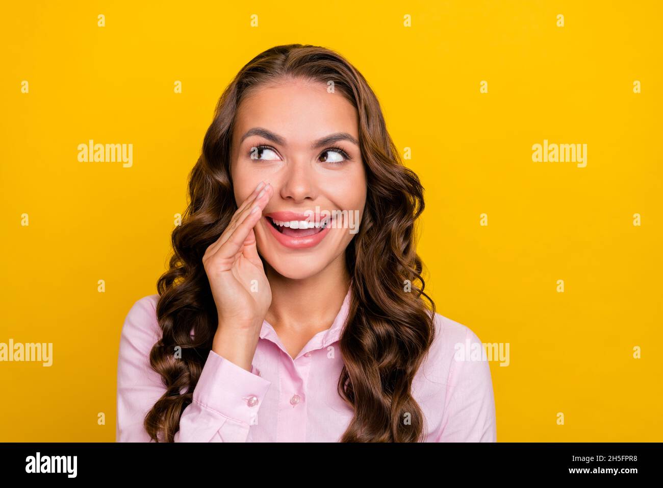 Foto di giovane bruna donna astuzia dire segreto indossare camicia rosa isolato su sfondo giallo Foto Stock
