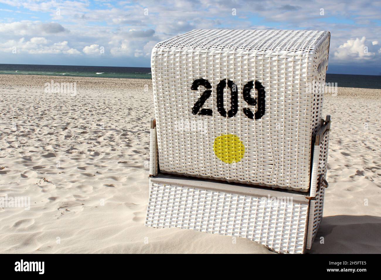 Ein Weißer, geflochtener Strandkorb von hinten mit Blick auf das Wasser am leeren Strand von Sylt, Deutschland. Foto Stock