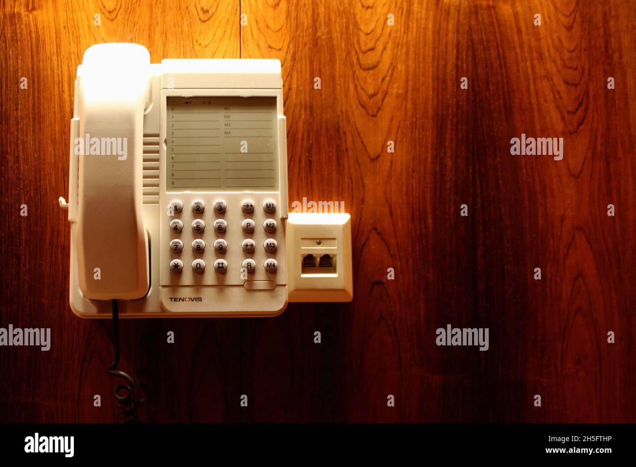 Altes Weißes Wandtelefon an einer holzvertäfelten Wand in einem alten Hotel. Foto Stock