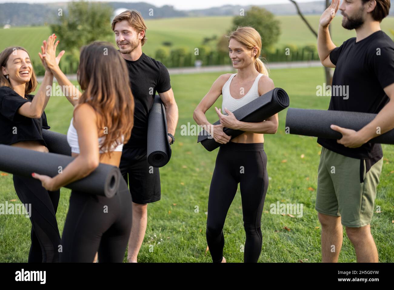 Le persone con materassini per il fitness si trovano in un prato verde Foto Stock